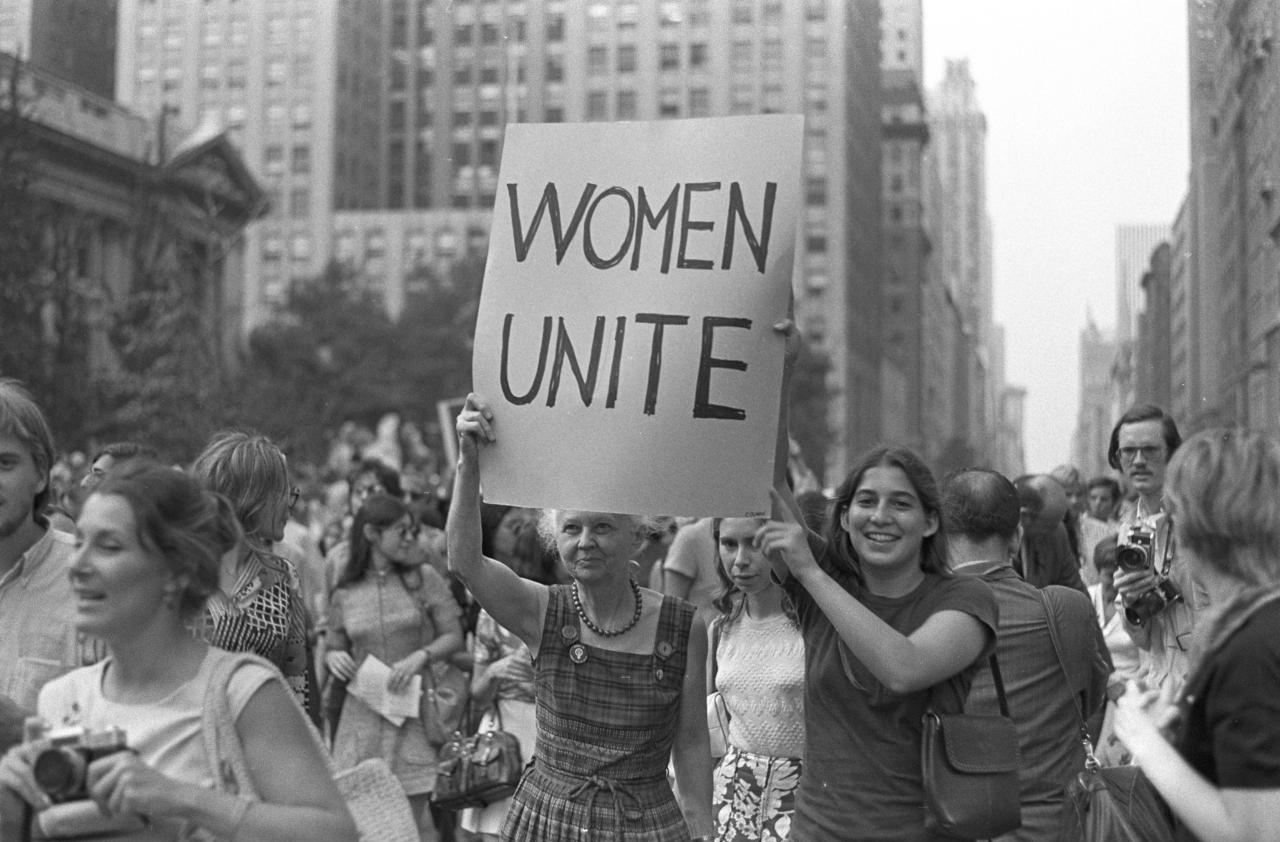 Two women hold up a sign "Women Unite" as they march down Fifth Avenue in New York City, New York.