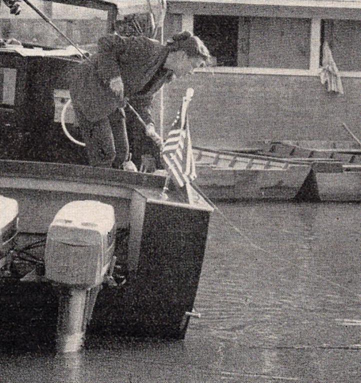 Virginia Kraft hangs over a boat reeling in a duck that incercepted her fishing cast.