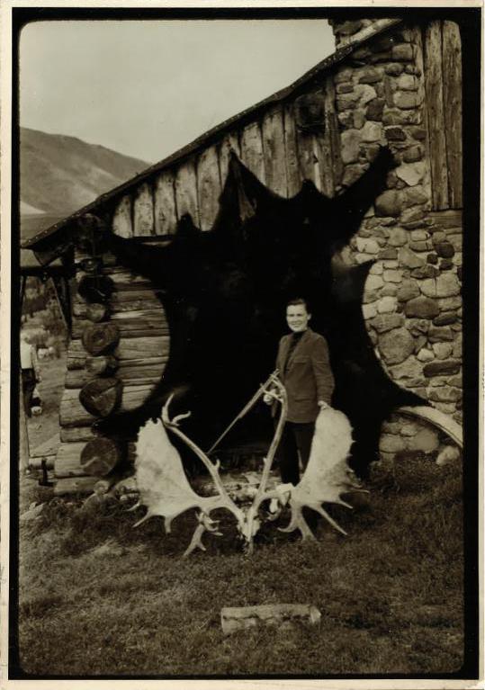 Virginia Kraft poses in front of a her kills, including a grizzly bear with a nine-foot hide, outside a lodge.