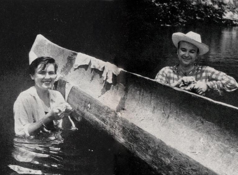 Virginia Kraft, waist deep in the water with guide Floyd Cranfil, drapes her wet laundry over the side of a canoe.