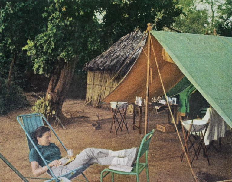Virginia Kraft lounges under a tent, reading a book, during a mid-day hunting break in Kenya.