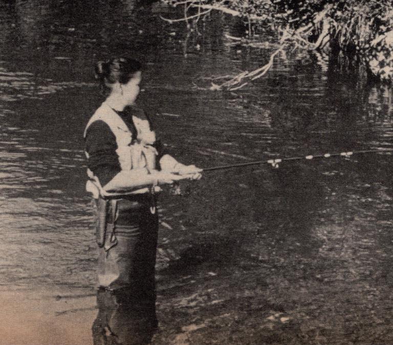 Virginia Kraft fishes for rainbow trout in Alaska, standing knee-deep in a stream.