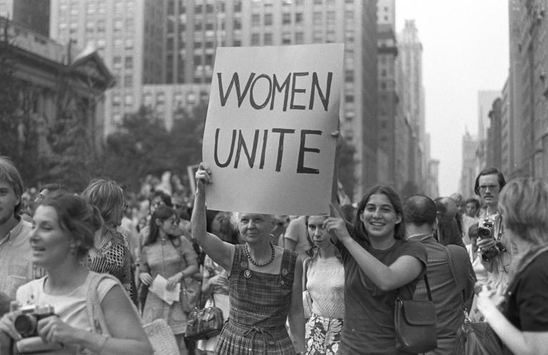 Two women hold up a sign "Women Unite" as they march down Fifth Avenue in New York City, New York.