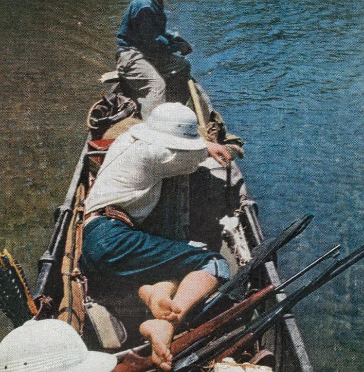 Virginia Kraft naps in a dugout canoe, surrounded by her husband, her guide, and several rifles. 