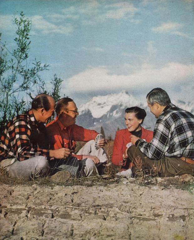 Three men and Virginia Kraft sit in a circle, playing cards against the Alaskan wilderness.