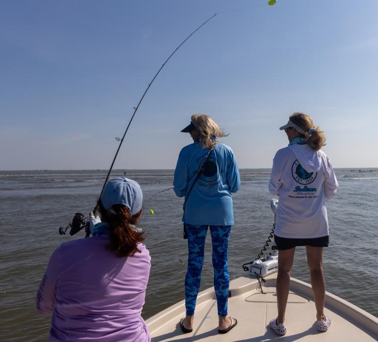 Three women fish off the bow of a fishing boat.
