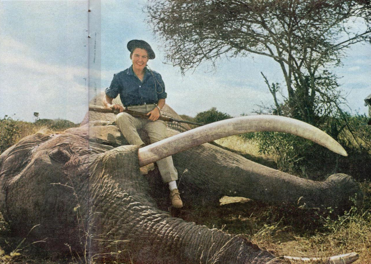 Virginia Kraft sits atop an African elephant, rifle in hand.